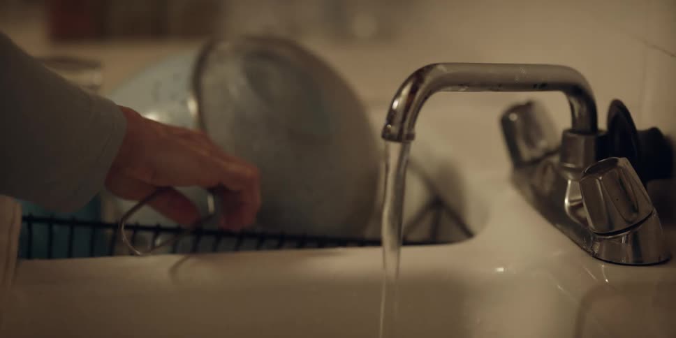 A woman washing dishes in a kitchen sink