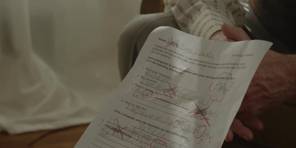 A student holding a graded school assignment with red marks