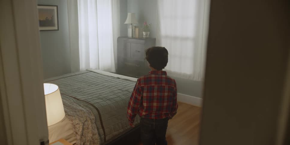 Sad boy wearing red plaid shirt enters bedroom throws himself on bed crying