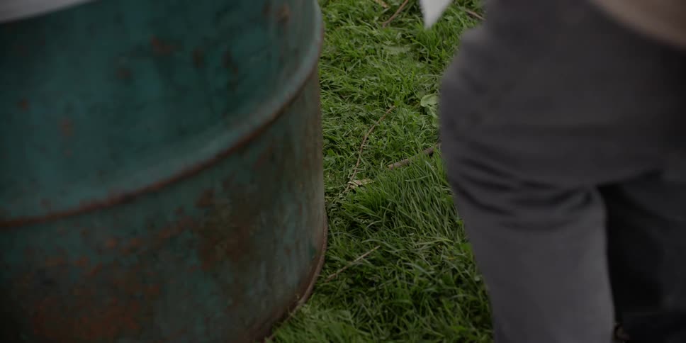 A person picks up trash near the garbage bin