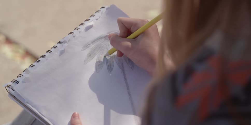 A female drawing a flour with a pencil in a sketchpad