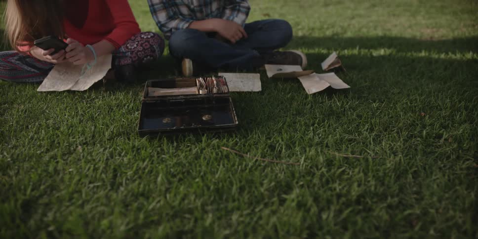 Two children look at documents from a box