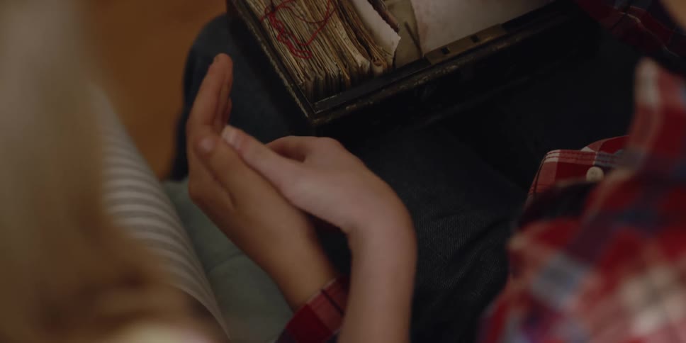 Woman holds hand to comfort person looking through box of old letters