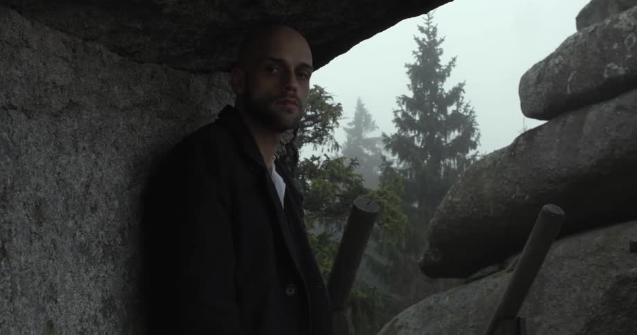 Man standing in a cave like area in the wilderness