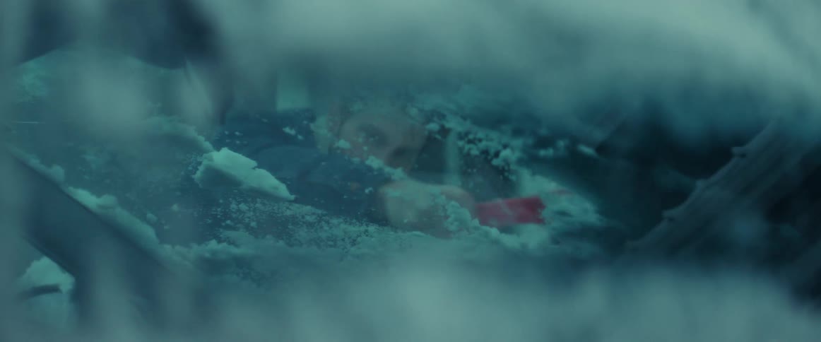 A man cleans snow off his vehicle with a scraper