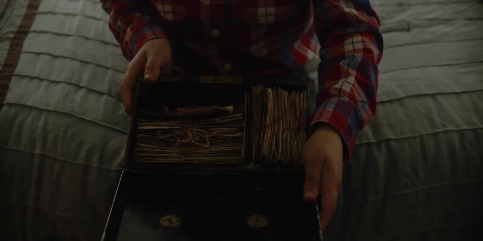 A mother hands her son a box full of letters and he sits on his bed and opens it and then she hands him a letter which he opens