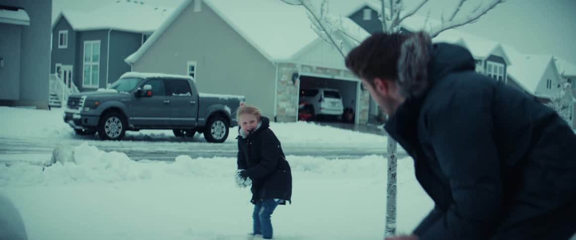 Father and daughter have snowball fight in snow covered front yard