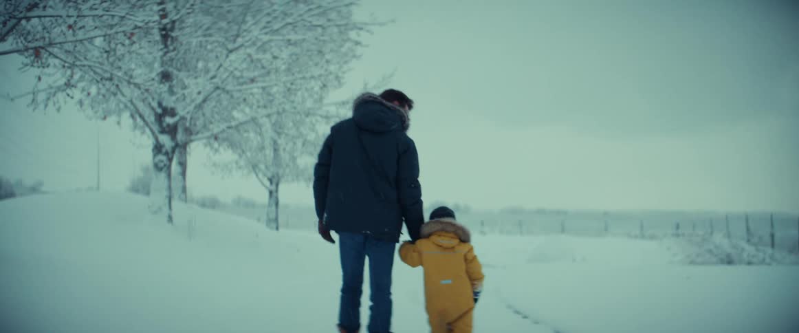 Man and son hold hands and walk through the snow