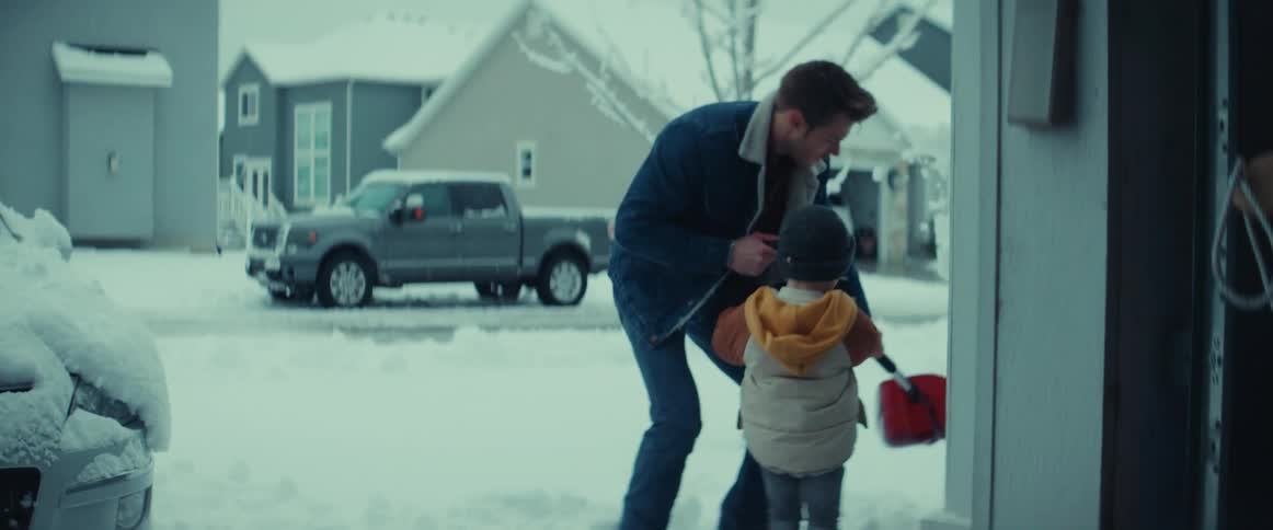 A father and young son shoveling a snowy driveway in winter
