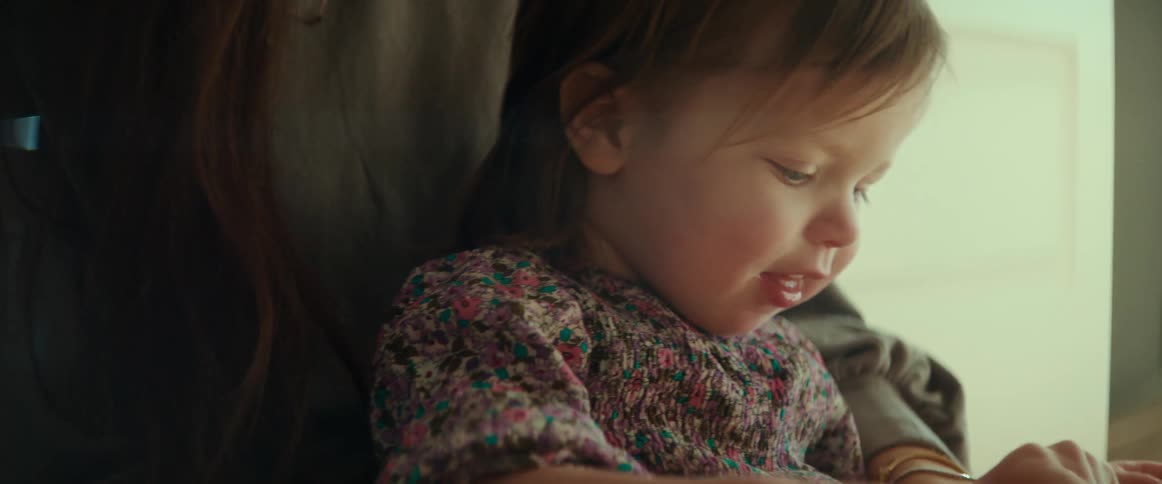 A mother and daughter are sitting down looking at a book together
