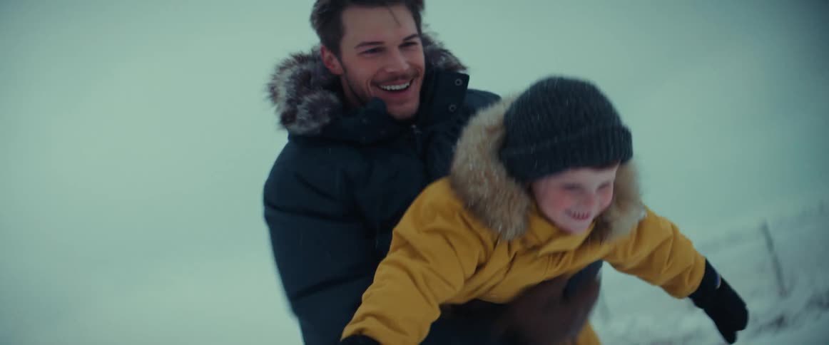 A father and son play in the snow