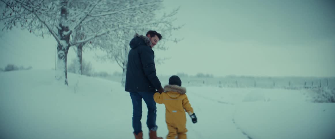 Father and son are holding hands and walking through the snow