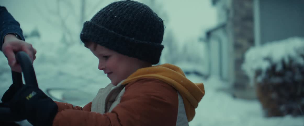 A father helping his young son clear snow with a snow shovel