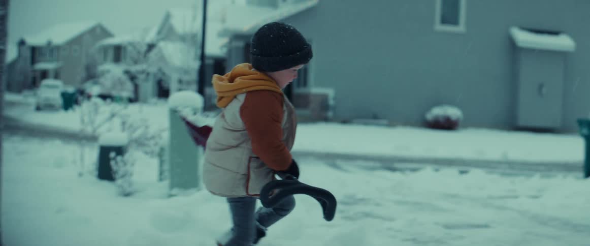 A young boy helping his father shovel snow off sidewalks on a winter day