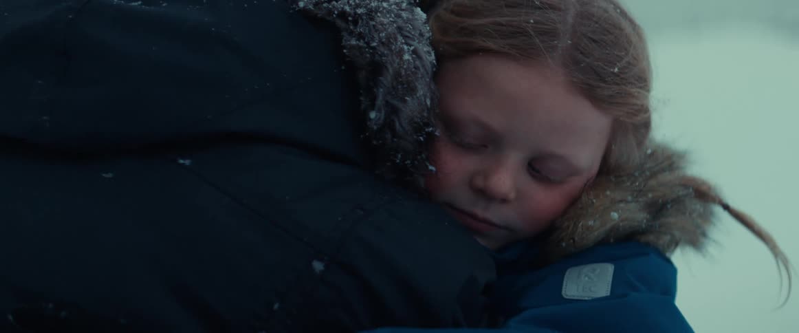 A parent holding their daughter outside on a cold snowy day