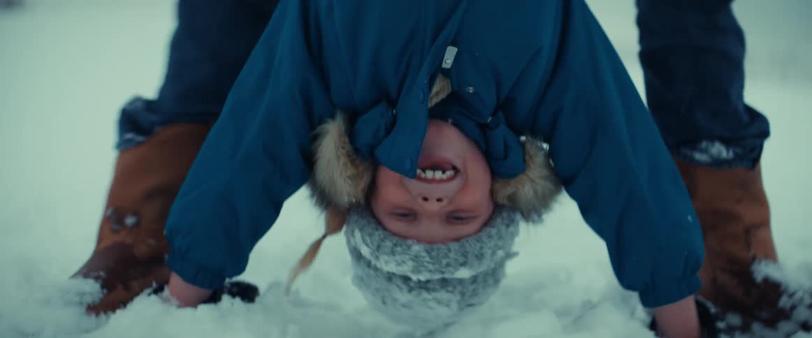 A father walking his son upside down on a snowy winter day