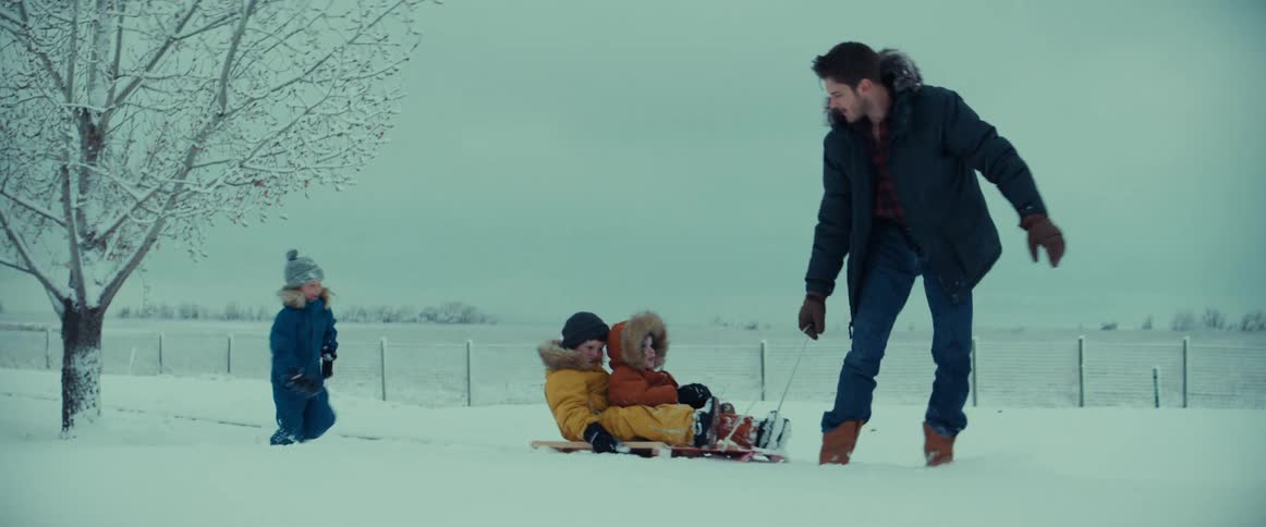 Man pulling his children through snow on a sled