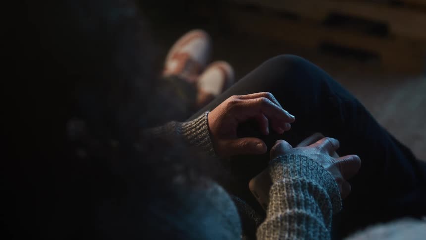 A woman is sitting with another person as she checks her cellphone then puts it down