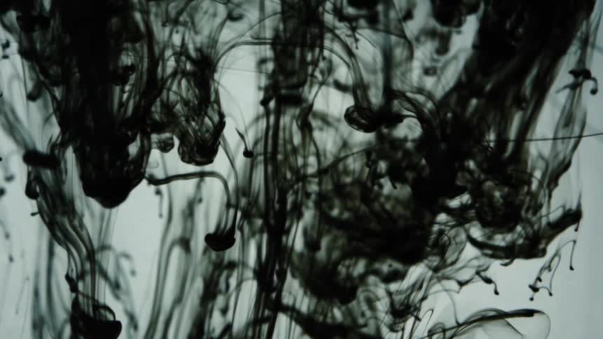 Black ink falls in a vat of water