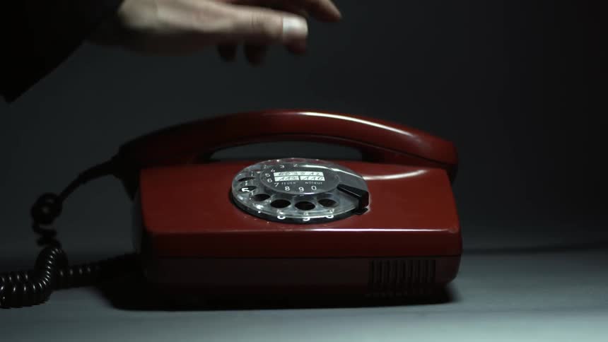 A man replaces the headset of an old rotary phone