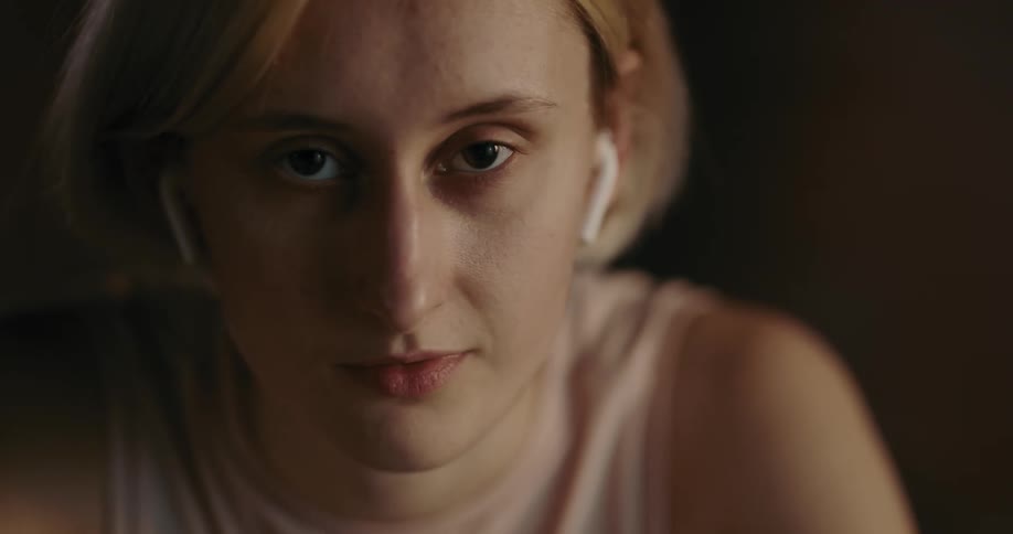 Light shines on the face of a young woman with brown eyes and short blond hair