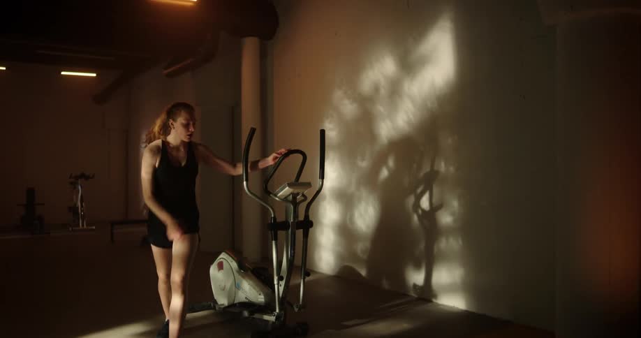 A woman is working out inside of a gym by herself