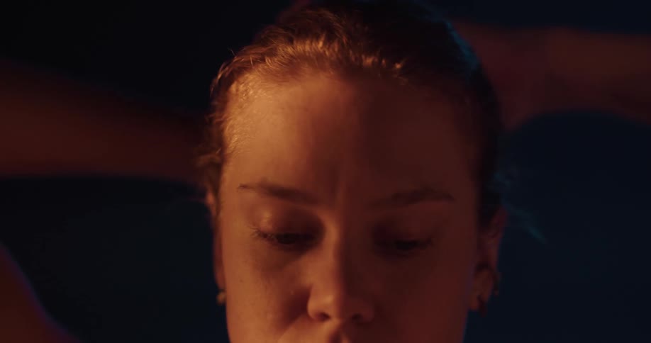Woman makes a ponytail looking at sunlight at gym