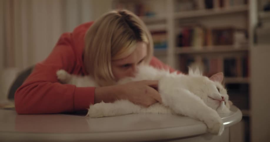 A woman buries her face in her cats stomach while petting it