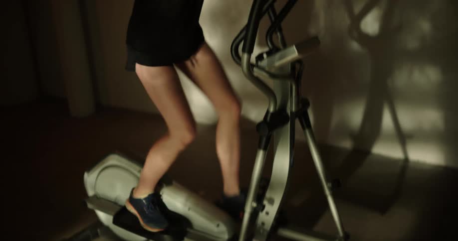 A woman rides an elliptical in the gym