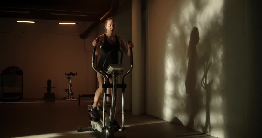A woman working out on an elliptical machine at the gym