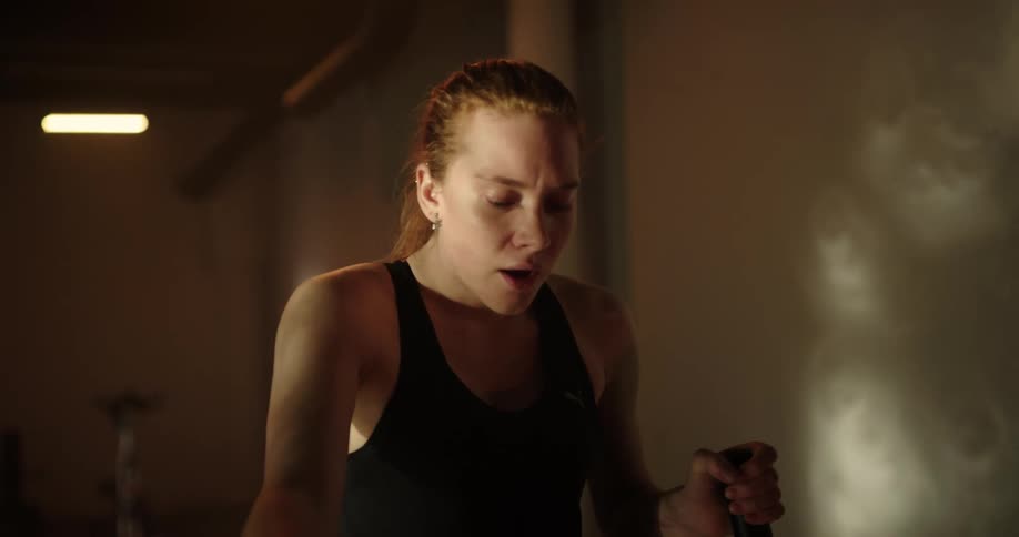 A female is exercising on an elliptical machine in an empty gym