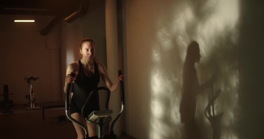 A woman exercising on an elliptical machine in a gym
