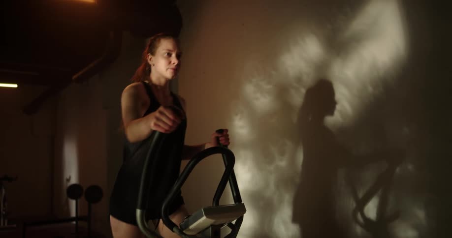 A woman is jogging on gym equipment indoors