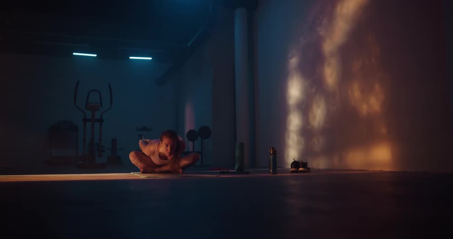 Woman with ponytail and white shirt stretches and does yoga at gym