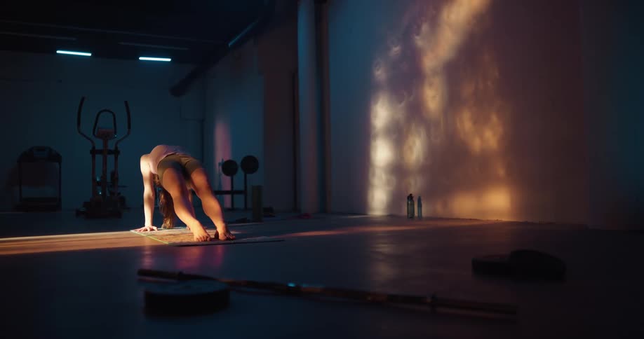 A woman doing yoga poses in a dark fitness room
