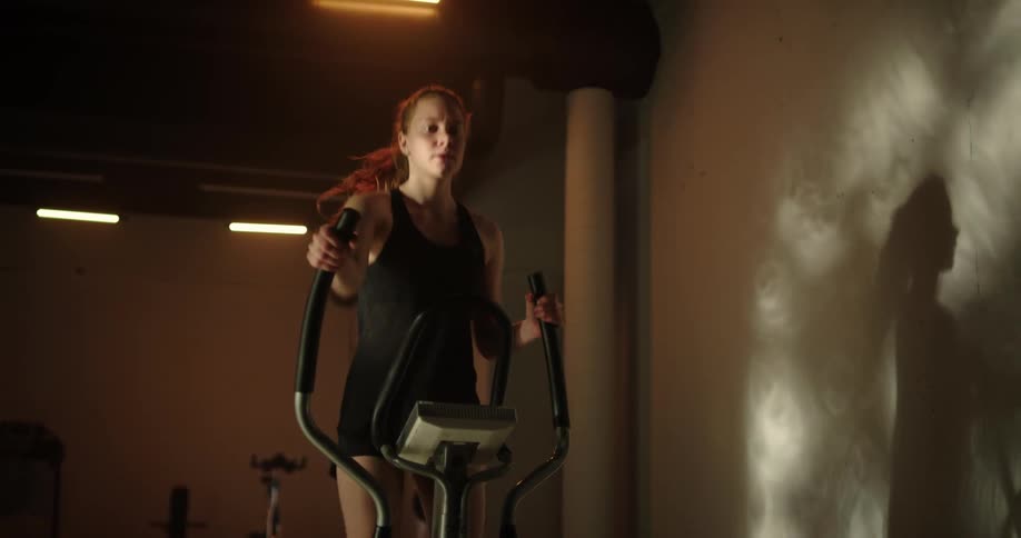 A young woman is working out at the gym by herself