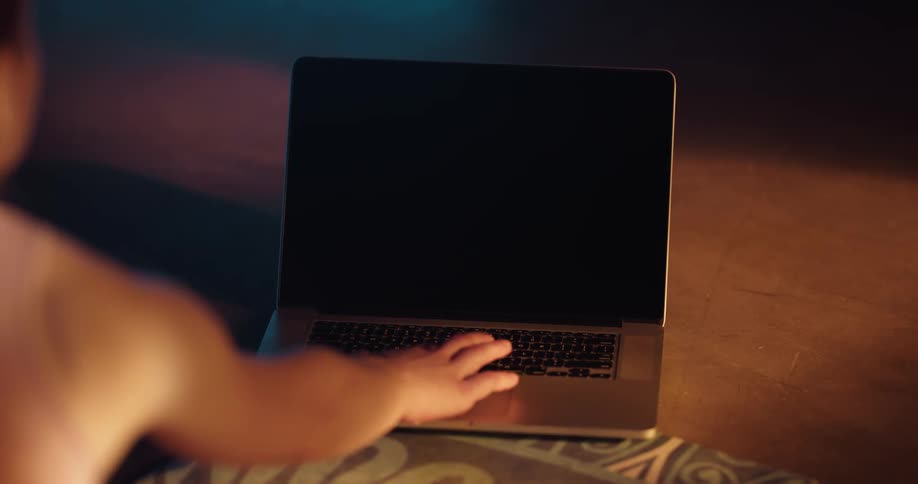 A woman pressing a button on an open laptop on the floor