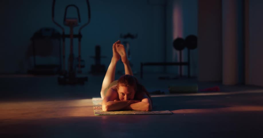 A young woman is doing yoga and laying on her mat