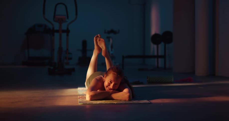 Redheaded woman lies on yoga mat smiling