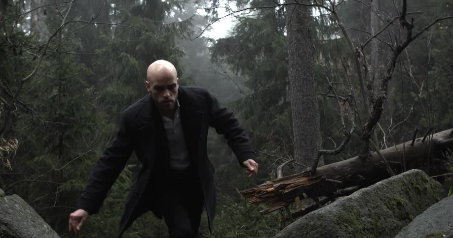 A man wearing a suit jacket hikes through the forest