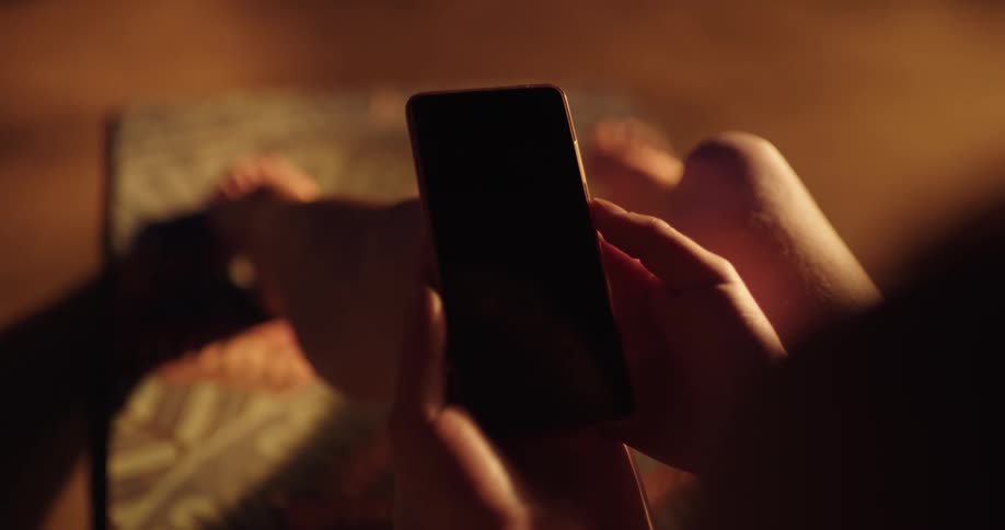 A woman is laying down in her bed and is on looking at her phone