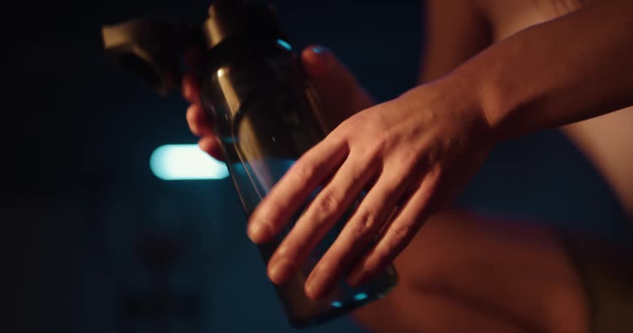 Woman crouches and takes a drink from a water bottle