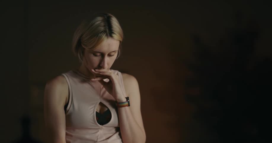 Sad contemplative woman sitting on a room reads a message on her smartphone