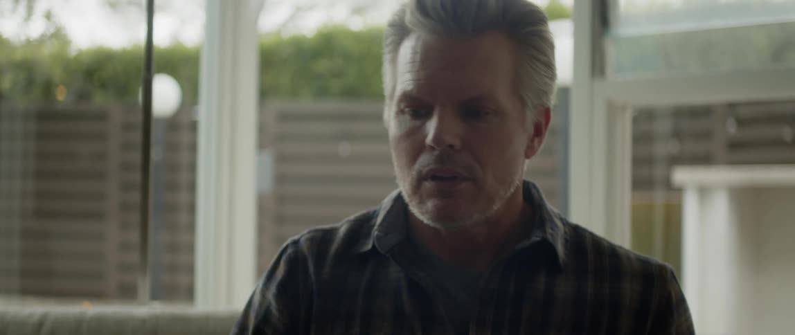 An older man looking frustrated and exhaling while sitting indoors