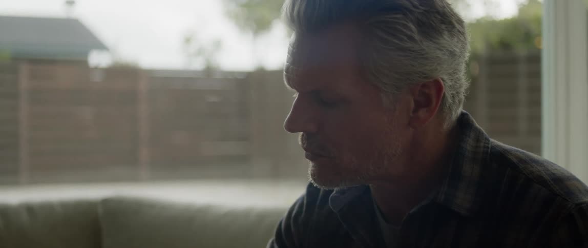 A man is sitting indoors next to a window during spring