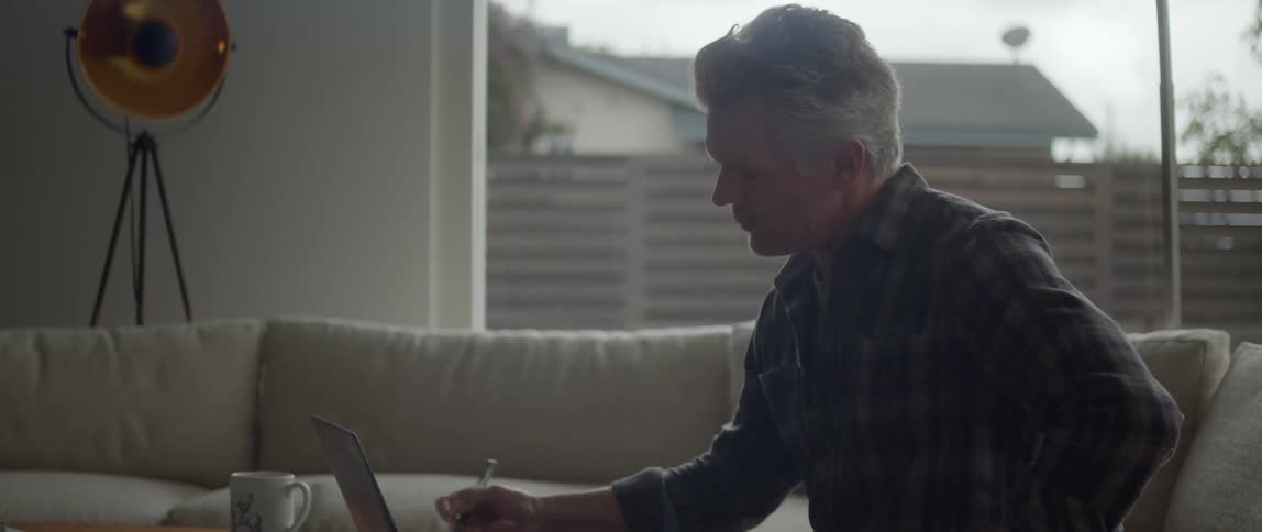There is an older man that is sitting down on his couch