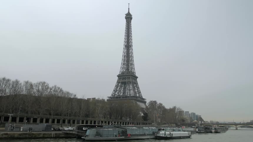 The eiffel tower towers over the city on an overcast day