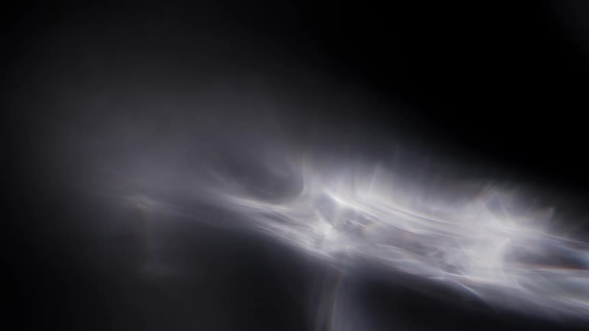 Wisps of light stretch across the darkness surrounded by an illuminated fog