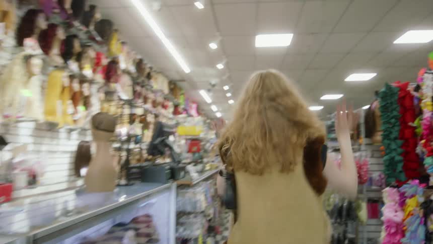 Young blonde woman happily dancing on the aisles of a store