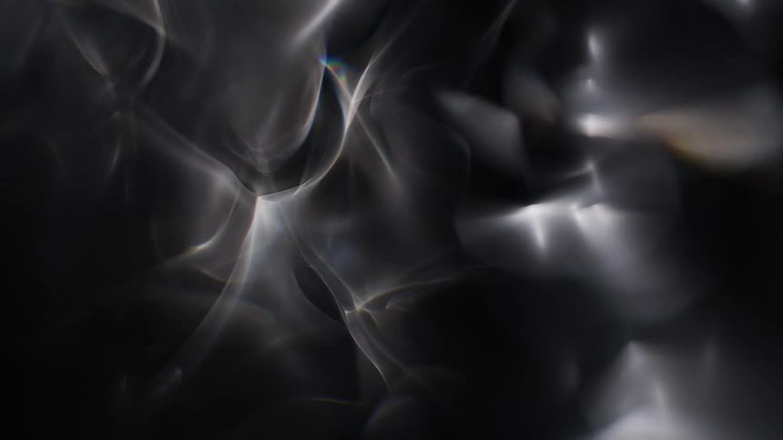 Close up of light being distorted reflecting on glass against a dark background